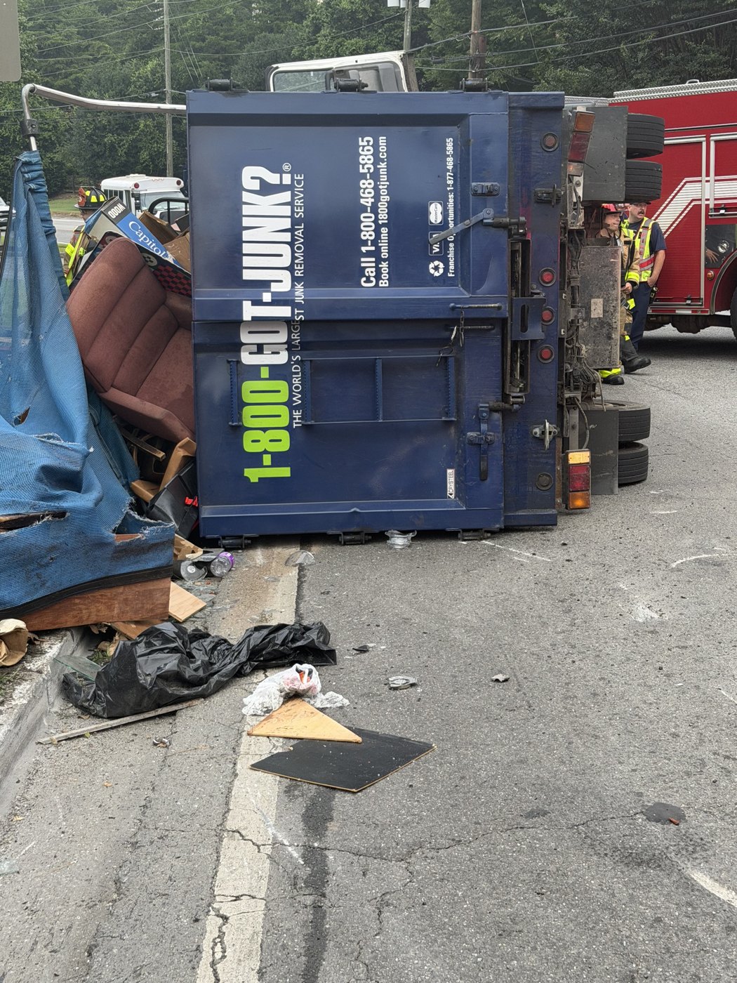 GOT-JUNK truck rolled onto its side in the road, load spilled, fire crew on scene